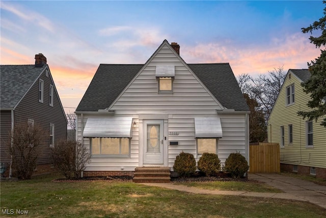 bungalow featuring a shingled roof, a front yard, and a chimney