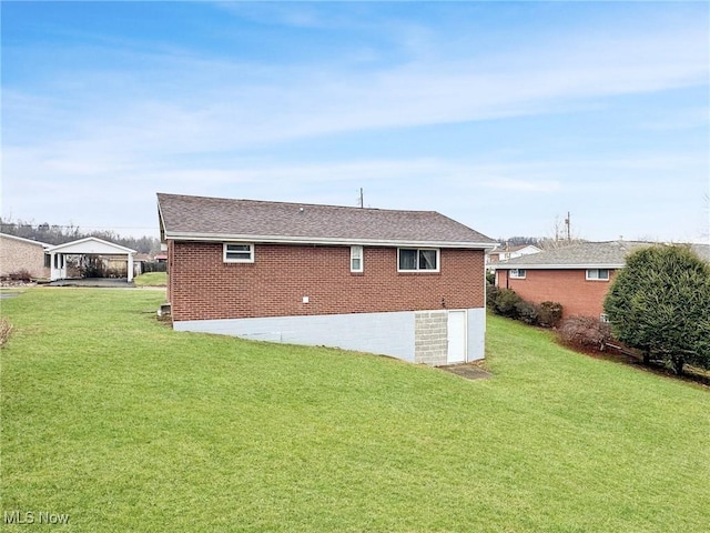 back of house with roof with shingles, a lawn, and brick siding