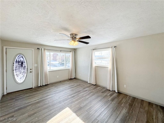 foyer entrance with a ceiling fan, a wealth of natural light, a textured ceiling, and wood finished floors