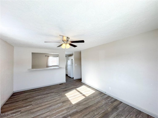 unfurnished room with a textured ceiling, wood finished floors, a ceiling fan, and baseboards