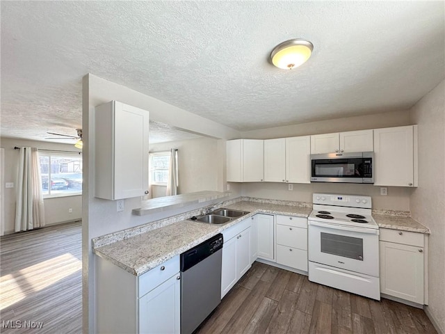 kitchen with dark wood-style flooring, light countertops, appliances with stainless steel finishes, white cabinets, and a sink