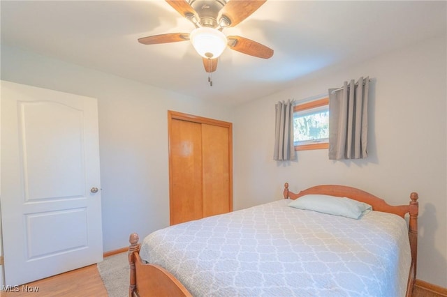 bedroom with light wood-type flooring, a closet, ceiling fan, and baseboards