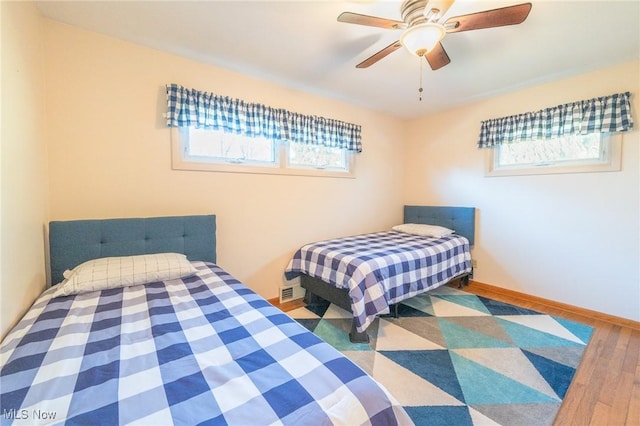 bedroom featuring ceiling fan, baseboards, and wood finished floors