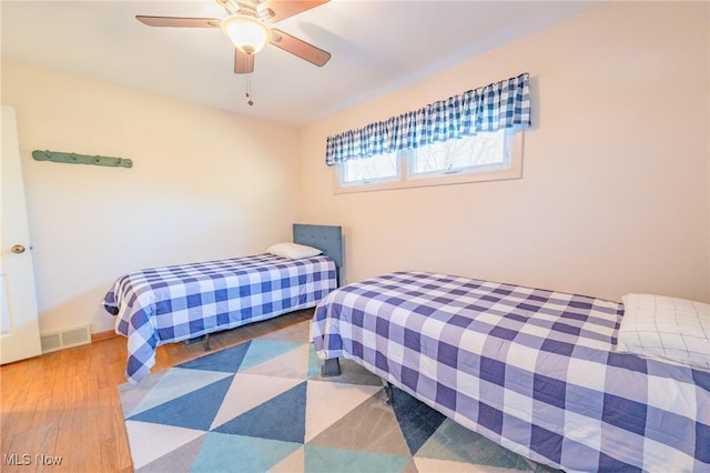 bedroom with a ceiling fan, visible vents, and wood finished floors