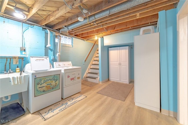 clothes washing area featuring light wood-style flooring, laundry area, and washer and clothes dryer