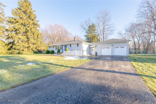 ranch-style house featuring driveway, a chimney, an attached garage, fence, and a front lawn