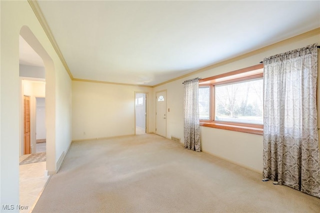 unfurnished room featuring arched walkways, light colored carpet, crown molding, and visible vents