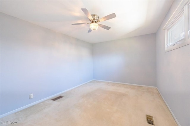 spare room featuring light carpet, baseboards, visible vents, and ceiling fan