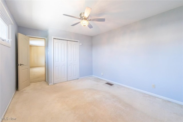 unfurnished bedroom with a closet, light colored carpet, visible vents, and baseboards