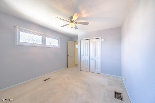 unfurnished bedroom with a closet, visible vents, light carpet, and baseboards