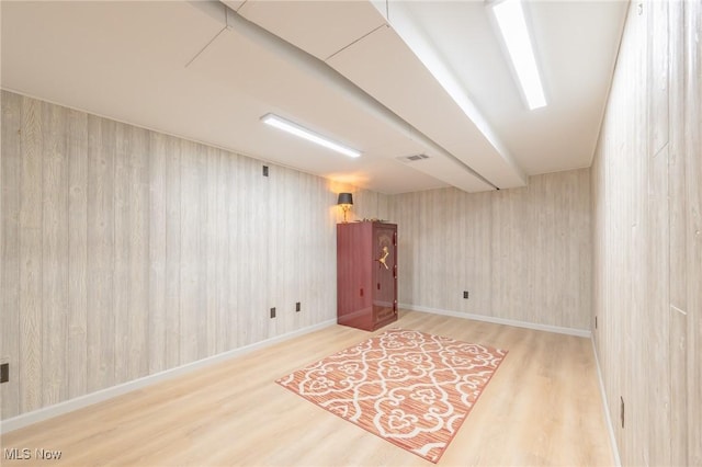 empty room with wood finished floors, visible vents, and baseboards