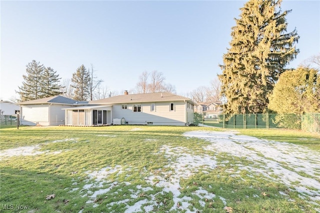 back of house featuring a sunroom, a chimney, fence, and a lawn