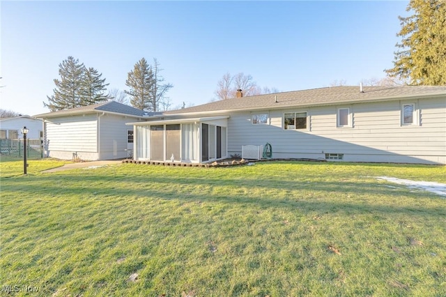 rear view of house featuring a yard, a chimney, and a sunroom