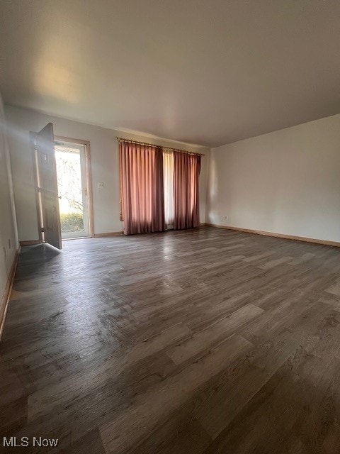 unfurnished room with dark wood-type flooring and baseboards