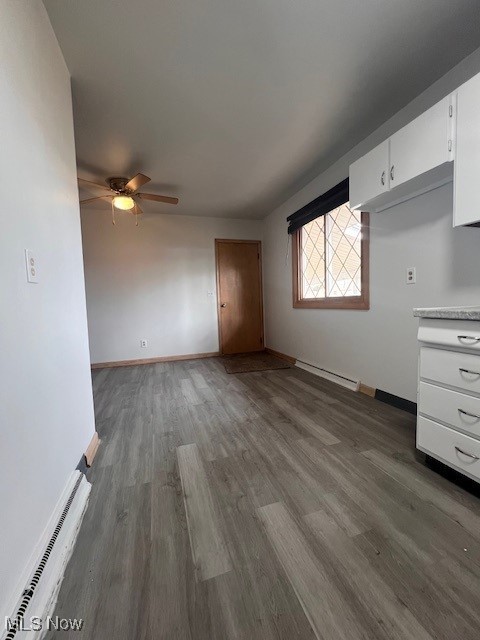 unfurnished living room with ceiling fan, baseboards, and wood finished floors