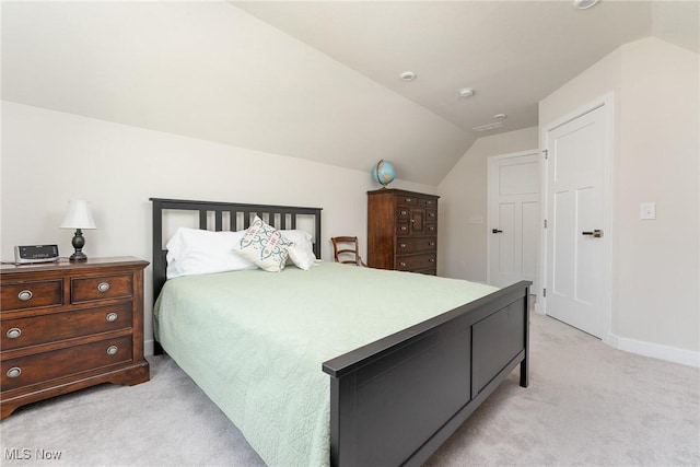 bedroom featuring light carpet, vaulted ceiling, and baseboards