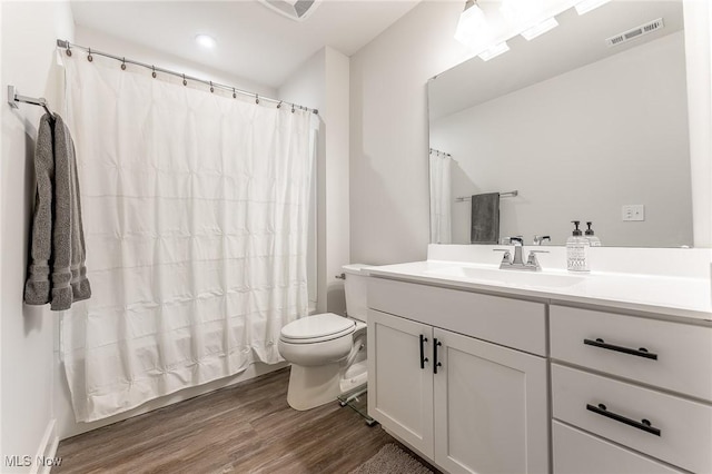 bathroom featuring visible vents, toilet, a shower with curtain, wood finished floors, and vanity