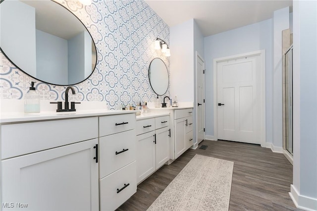 bathroom with a stall shower, wood finished floors, vanity, and wallpapered walls