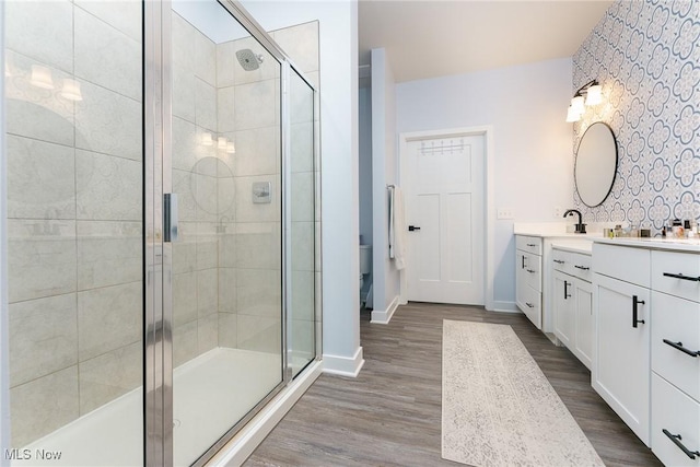 full bathroom with baseboards, a shower stall, vanity, and wood finished floors