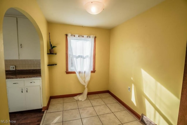 unfurnished dining area featuring light tile patterned flooring, visible vents, and baseboards