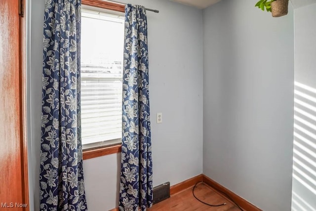 spare room featuring wood finished floors, a wealth of natural light, and baseboards