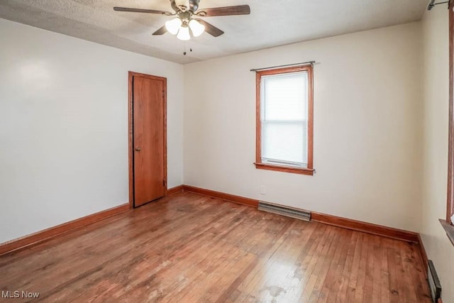 spare room featuring visible vents, baseboards, light wood-style flooring, ceiling fan, and a textured ceiling