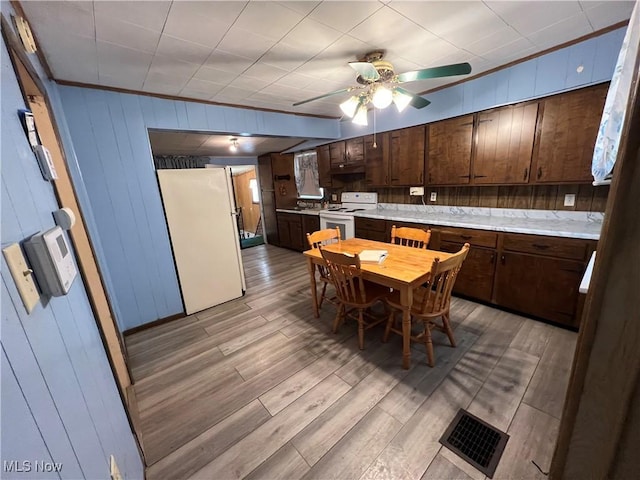 kitchen with dark brown cabinetry, white appliances, visible vents, light countertops, and light wood finished floors