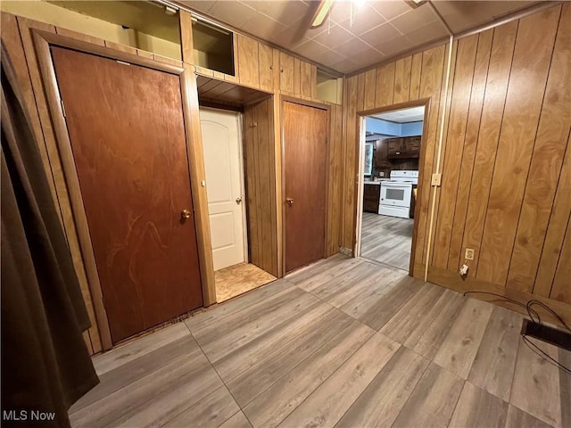 corridor with wood walls and light wood finished floors