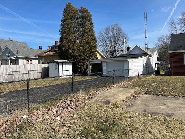 view of front facade with driveway, a storage shed, a detached garage, fence, and an outdoor structure