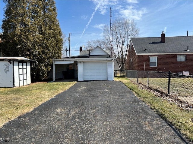 garage with a storage unit, driveway, a carport, and fence