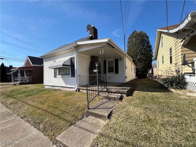 bungalow-style house with covered porch, a chimney, and a front lawn