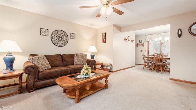 carpeted living room featuring baseboards and ceiling fan with notable chandelier