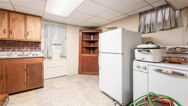 kitchen with white appliances, a sink, light countertops, brown cabinets, and light floors