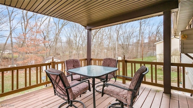 wooden terrace featuring an outbuilding, a yard, and outdoor dining area