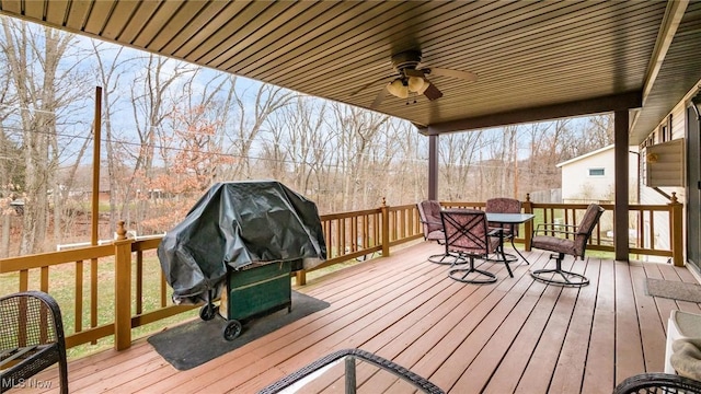 wooden terrace with a ceiling fan, outdoor dining space, and a grill