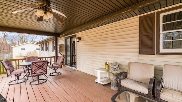 wooden deck with outdoor dining area and a ceiling fan