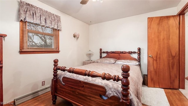 bedroom featuring a ceiling fan, a baseboard radiator, and wood finished floors