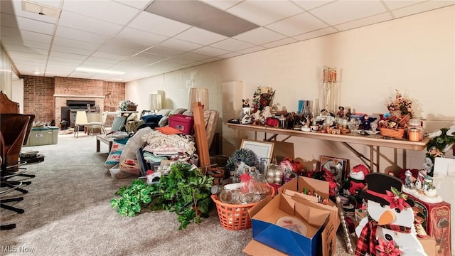 misc room featuring carpet, a paneled ceiling, and a brick fireplace