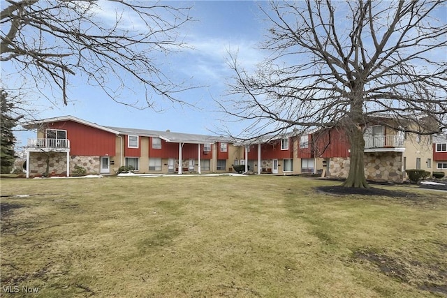 exterior space featuring stone siding and a yard