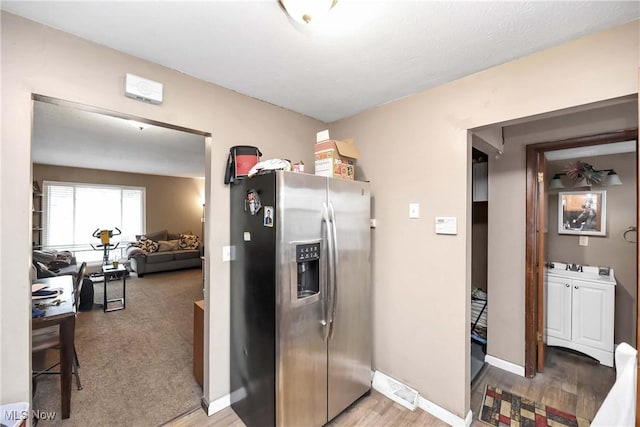 kitchen with light wood-style flooring, stainless steel refrigerator with ice dispenser, and baseboards