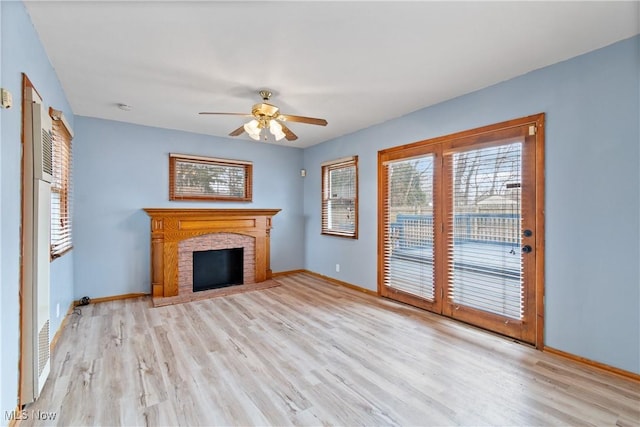 unfurnished living room featuring a ceiling fan, baseboards, a fireplace, and light wood finished floors