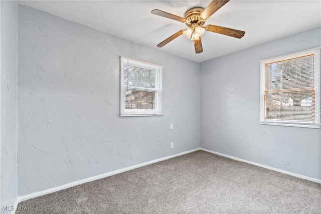 unfurnished room featuring a ceiling fan, carpet, a textured wall, and baseboards