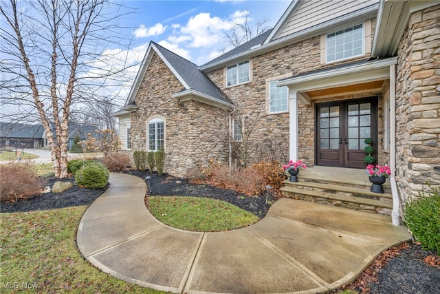 view of exterior entry with french doors and roof with shingles