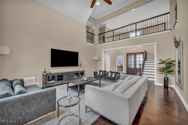 living room featuring stairway, a high ceiling, ceiling fan, wood finished floors, and baseboards