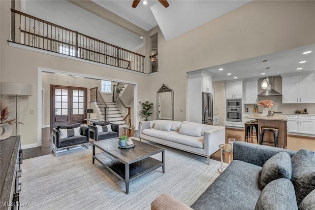 living room with light wood finished floors, stairs, a high ceiling, and french doors