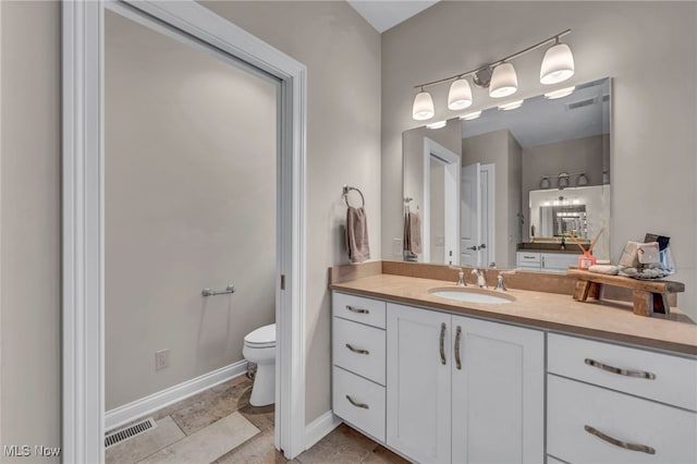 bathroom featuring toilet, baseboards, visible vents, and vanity