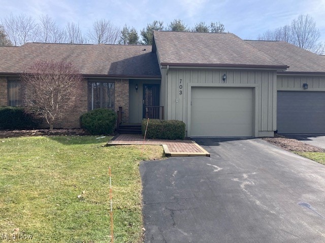 single story home featuring a garage, a shingled roof, aphalt driveway, board and batten siding, and a front yard