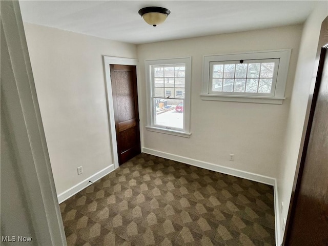 interior space with dark carpet and baseboards