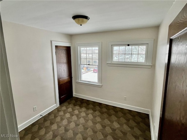 unfurnished bedroom featuring baseboards and dark carpet