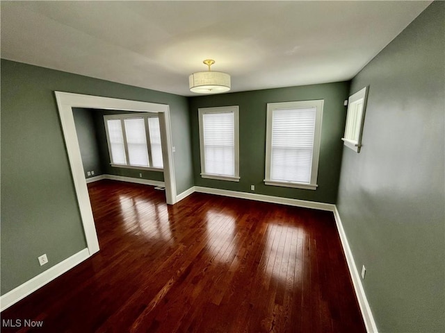 unfurnished room with dark wood-style flooring and baseboards